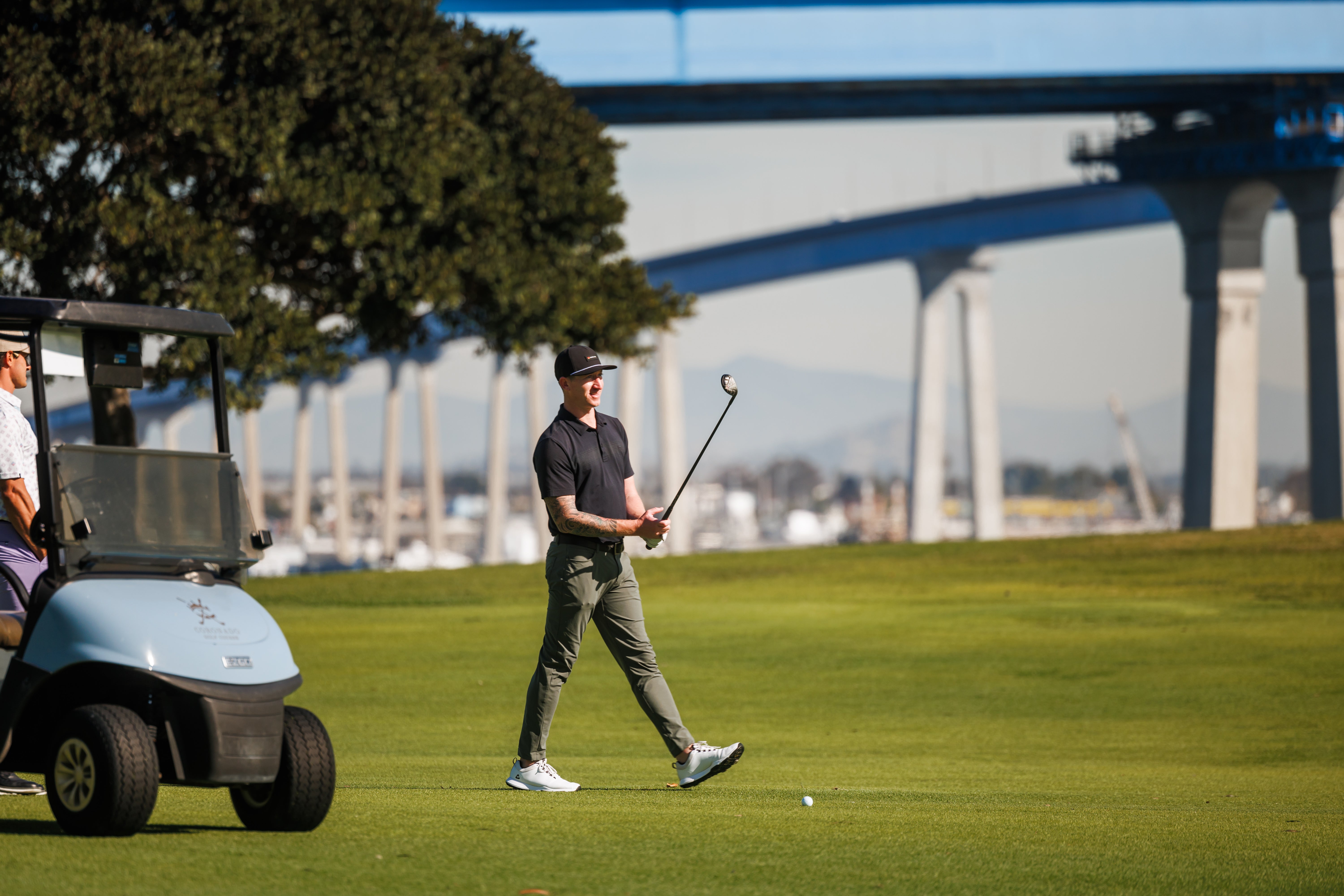 Person playing golf on a green course with a bridge in the background